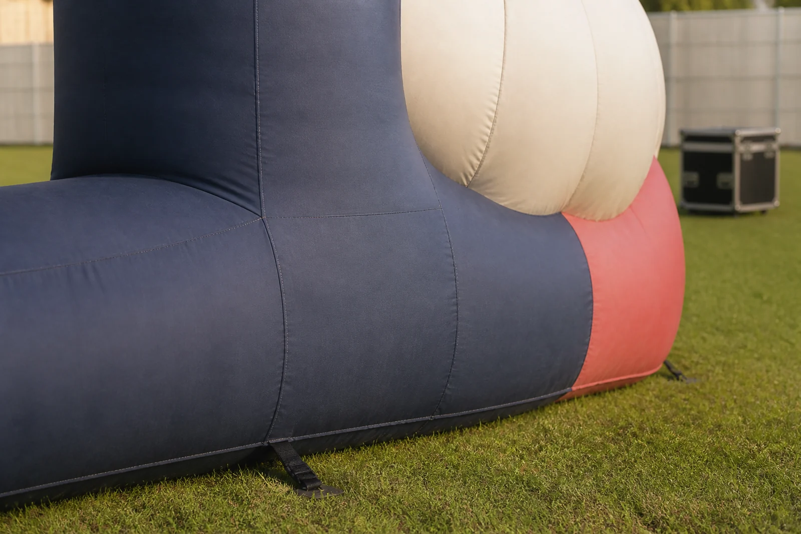 Close view of the grounded navy, cream, and coral base of an outdoor inflatable landmark.